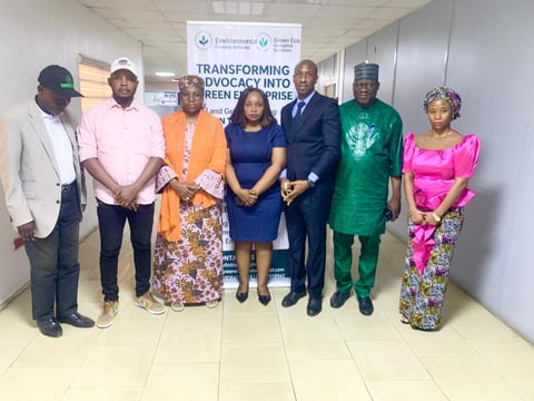 Group of eight people standing in a line indoors with a banner reading Transforming Advocacy Into Green Pulse visible behind them